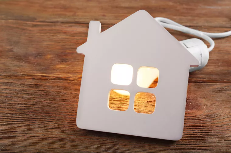 Bulb and shape of home on wooden background<br>električna energija, kuća, kuće, kućanstva, kućanstvo, opskrba struja