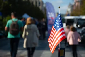 New York, USA - September 19 2020American flag waving on the car on the 4th of July, thanksgiving day or during United States Presidential election, 11 September, with people and cars on background<br>Amerika, SAD, midterms, međuizbori
