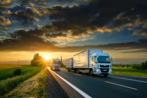 PRILOG<br>Transport, &scaron;pedicija i izvoznici<br>Overtaking trucks on an asphalt road in a rural landscape at sunset