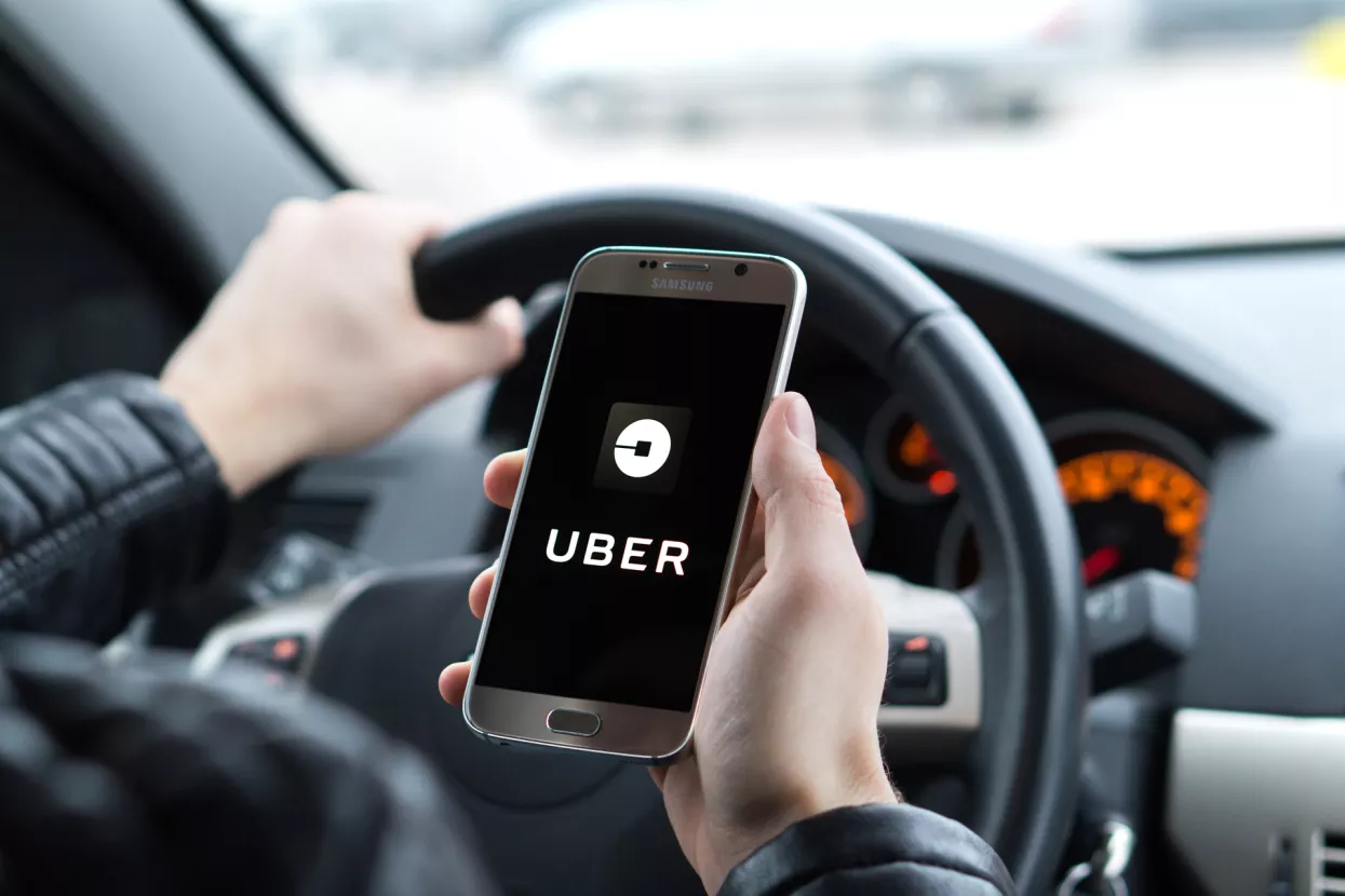 JYVASKYLA, FINLAND - DECEMBER 7, 2017Uber driver holding smartphone in car. Uber is an American company offering transportation services online. Illustrative editorial.