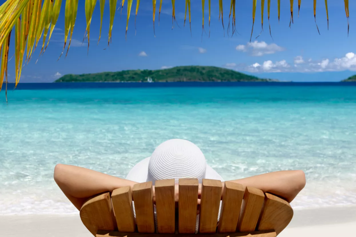 woman sunbathing in a teak chair on a beautiful Caribbean beach