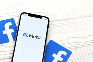 KHARKOV, UKRAINE - OCTOBER 29, 2021Iphone 12 Pro with Meta or MetaVerse logo lies on wooden table with two paper Facebook logos.