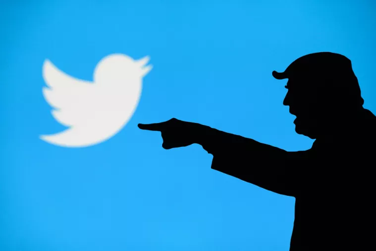 NEW YORK, USA, SEPTEMBER 25, 2020 Donald Trump versus Twitter. Silhouette of angry American President in conflict with Chinese social network Twitter. Logo of company on blue screen in background