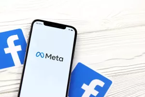 KHARKOV, UKRAINE - OCTOBER 29, 2021Iphone 12 Pro with Meta or MetaVerse logo lies on wooden table with two paper Facebook logos.