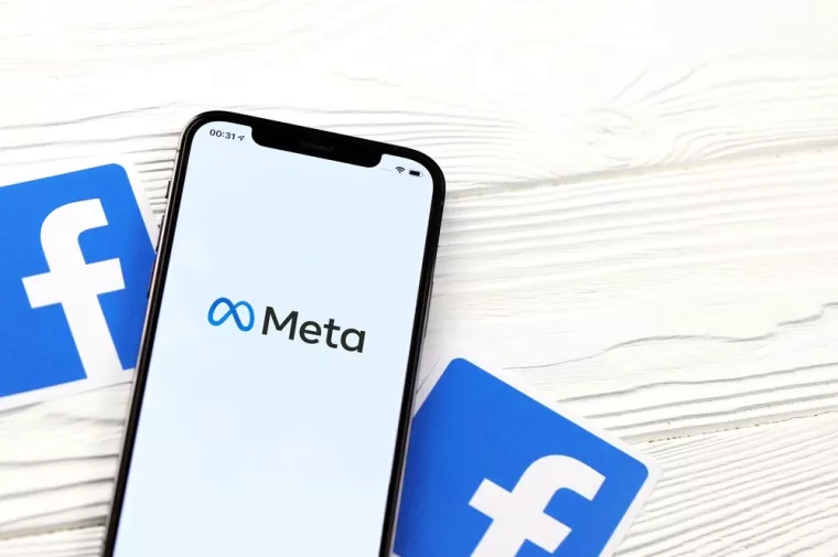 KHARKOV, UKRAINE - OCTOBER 29, 2021Iphone 12 Pro with Meta or MetaVerse logo lies on wooden table with two paper Facebook logos.