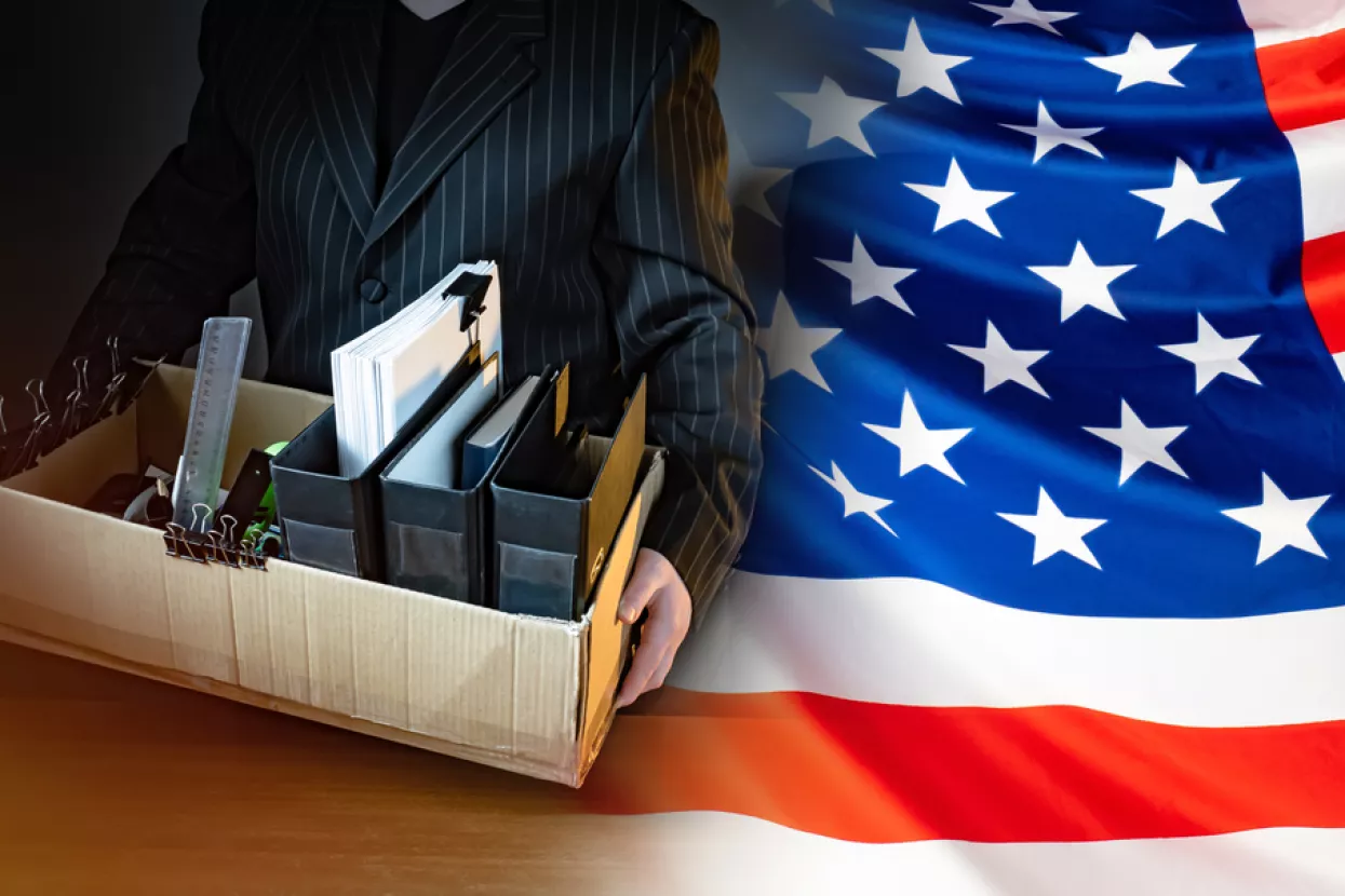 Unemployed. Man holds a box with personal belongings. USA flag. Concept - unemployed American. American was fired. USA resident is unemployed. Stationery in a cardboard box. American labor market amerikasad, zaposlenost, stopa zaposlenosti, posao, poslovi