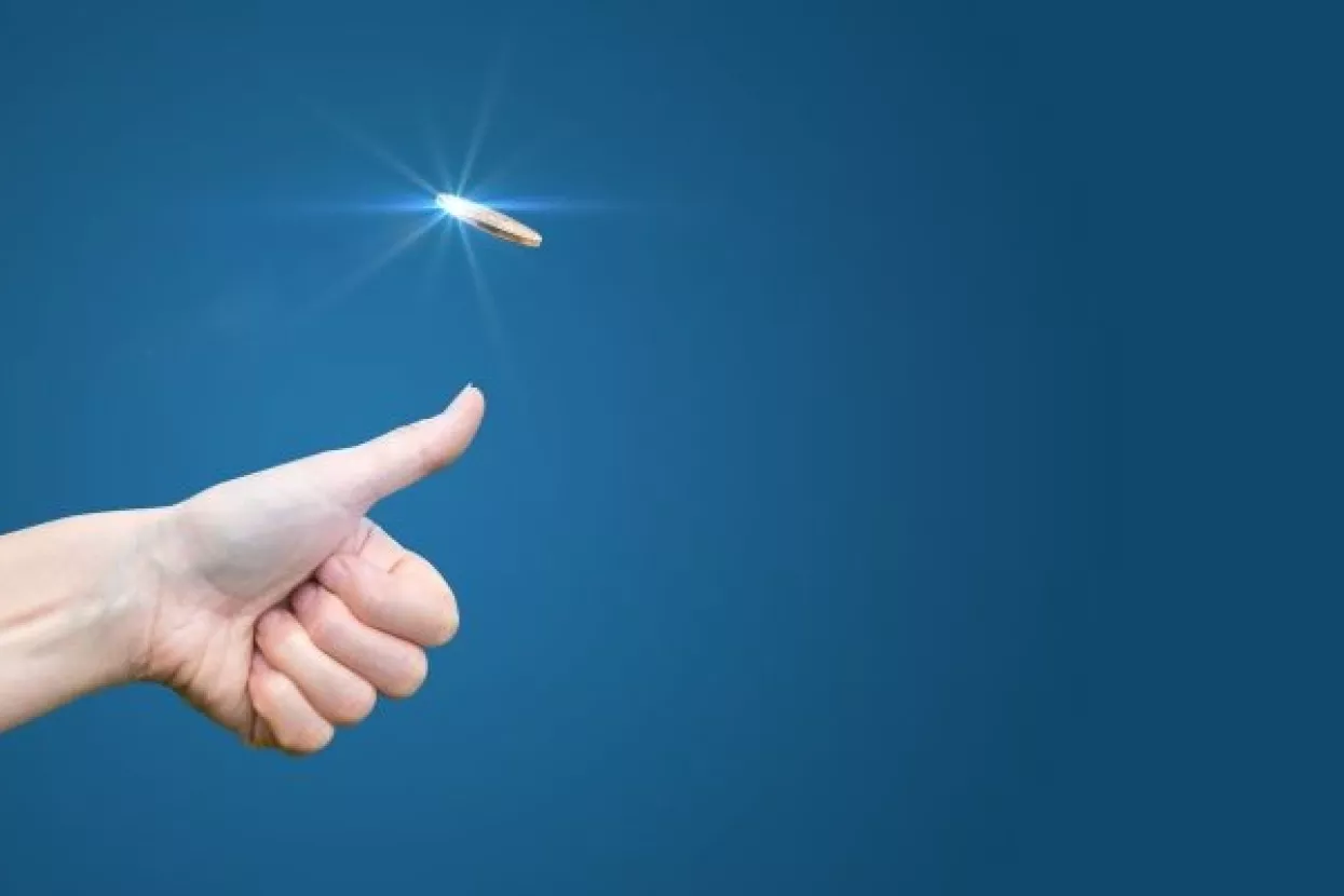 hand throws a coin on a blue background to make the decision