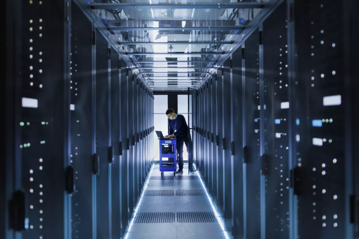 IT Engineer With Crash Cart Puts Hard Drives into Open Rack Server Cabinet. He's Working in Big Data Center.