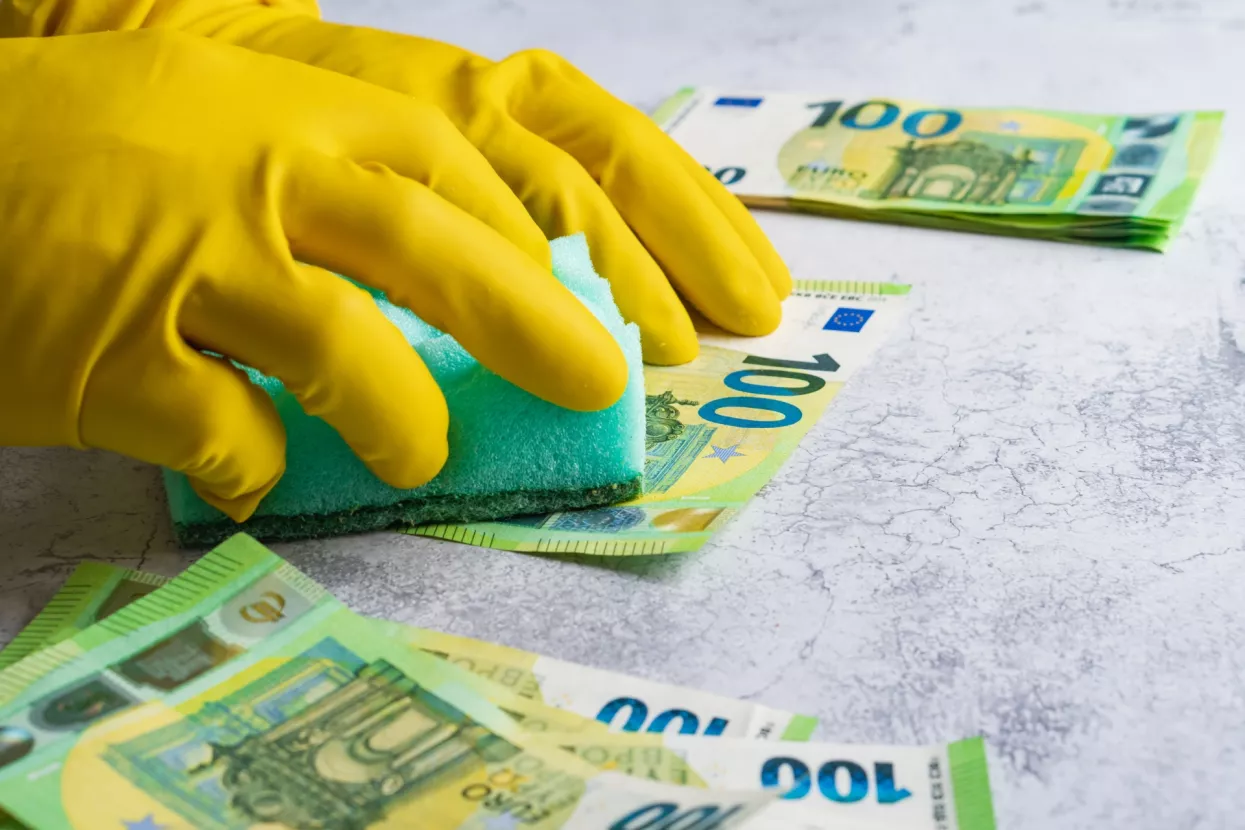 Pranje novca - ilustracijaLaundering of money. Man in yellow gloves washes papper hundred 100 euro with green washcloth