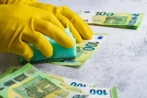 Pranje novca - ilustracijaLaundering of money. Man in yellow gloves washes papper hundred 100 euro with green washcloth
