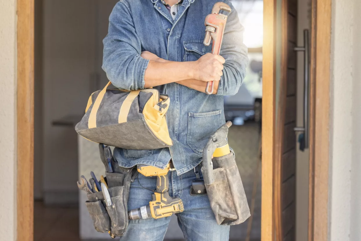 Handyman, tool bag and arms crossed at work with goals, property development and real estate maintenance. Construction worker, tools and renovation industry with service, vision and home improvement
