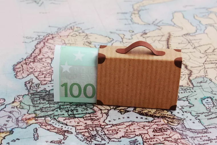 Europe city trip travel budget concept with 100 euro note and suitcase on map