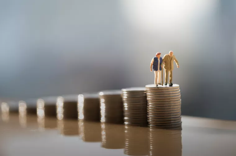 Concept of retirement planning. Miniature people: Old couple figure standing on top of coin stack.mirovinski fondovi